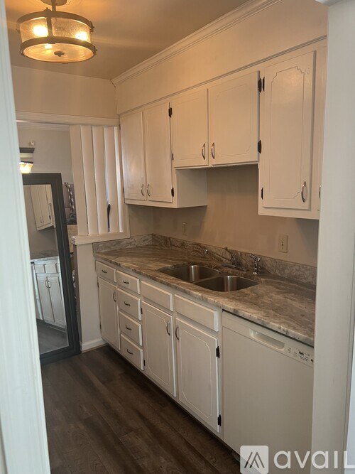 A kitchen with white cabinets and a marble countertop.