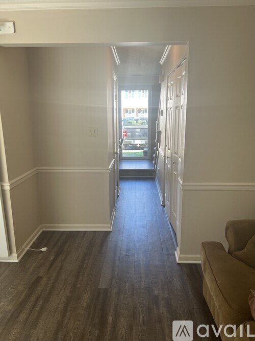 A hallway with wood flooring and white walls.