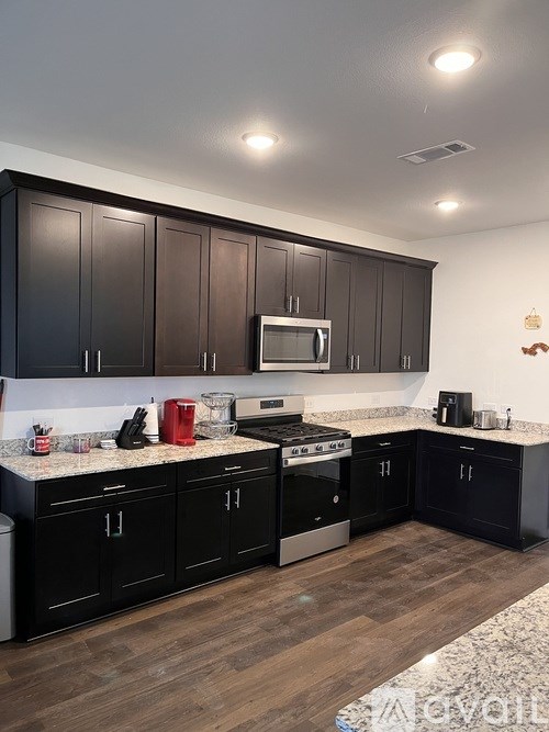 A kitchen with black cabinets and a granite countertop.
