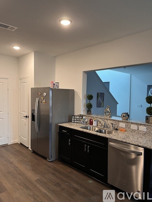 A kitchen with a black fridge and stainless steel sink.
