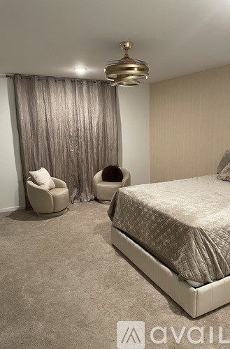 A bedroom with a bed, chair, and curtains.