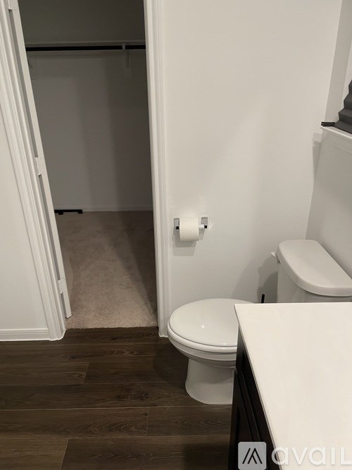 A white toilet in a small bathroom with wood flooring.