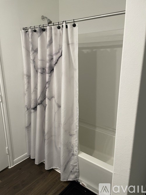 A shower curtain with a marble pattern hangs in a bathroom.