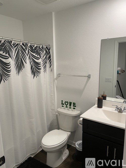 A bathroom with a toilet, sink, and shower curtain.