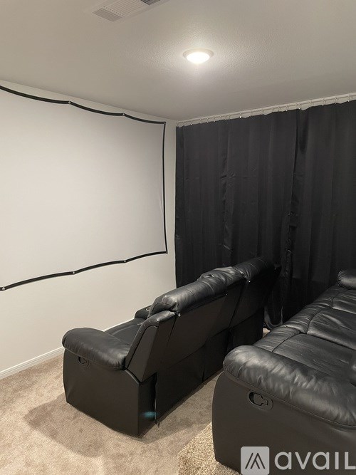A black leather sofa in a room with a white wall and a black curtain.