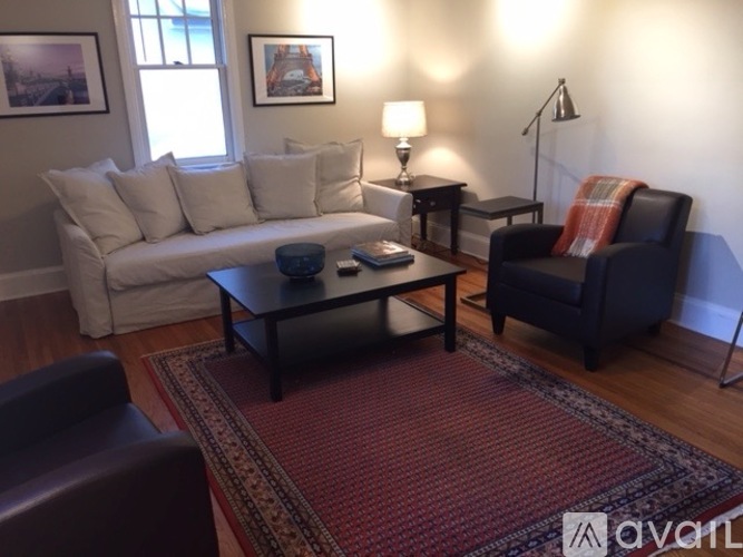 A living room with a white couch, a black chair, and a red rug.