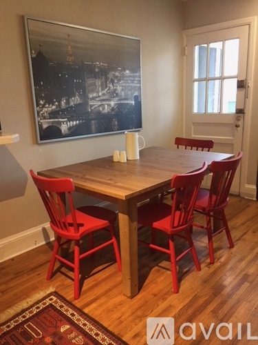 A dining room with a wooden table and red chairs.