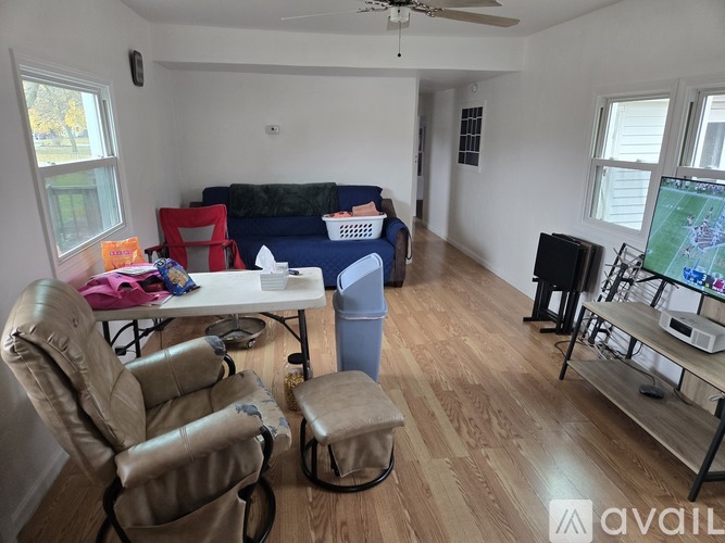 A living room with a blue couch, a table with chairs, and a television.