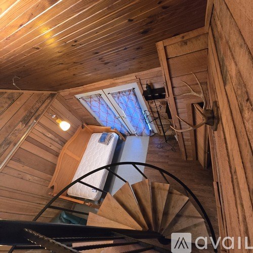 A spiral staircase in a wooden building with a skylight above it.
