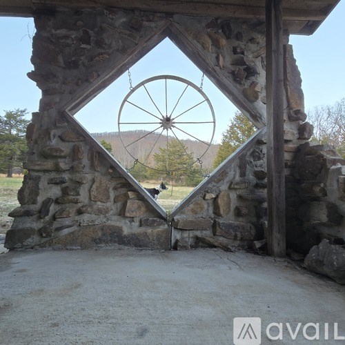 A stone structure with a large wheel in the background.
