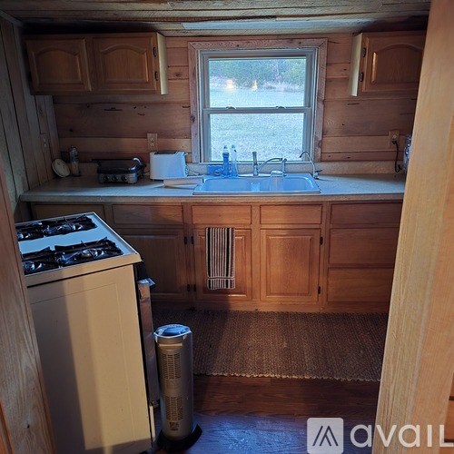 A small kitchen with a stove, sink, and window.