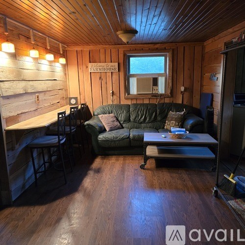 A living room with a green couch and wooden walls.