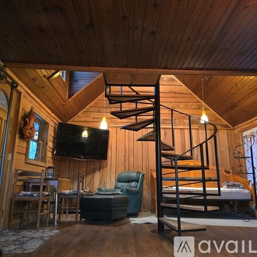A wooden cabin with a spiral staircase and a flat screen TV mounted on the wall.