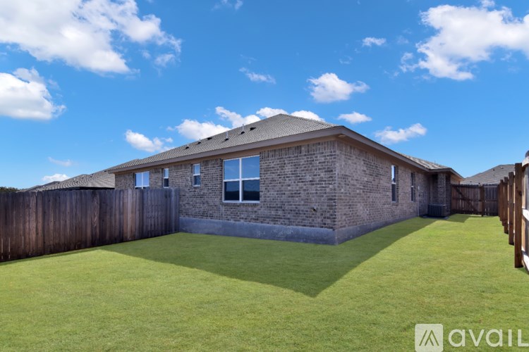 A backyard with a wooden fence and a house with a brown roof.