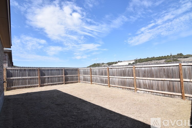 A backyard with a wooden fence and a gravel ground.