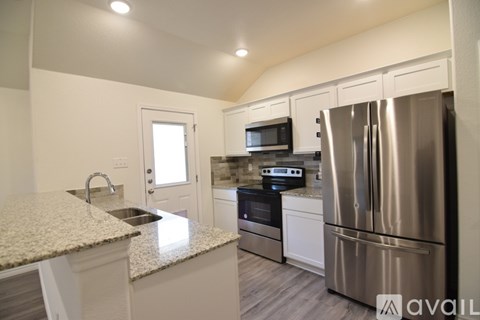 A kitchen with a granite countertop and stainless steel appliances.