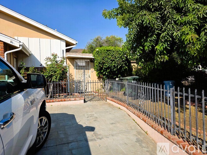 A white car is parked on a driveway in front of a house.