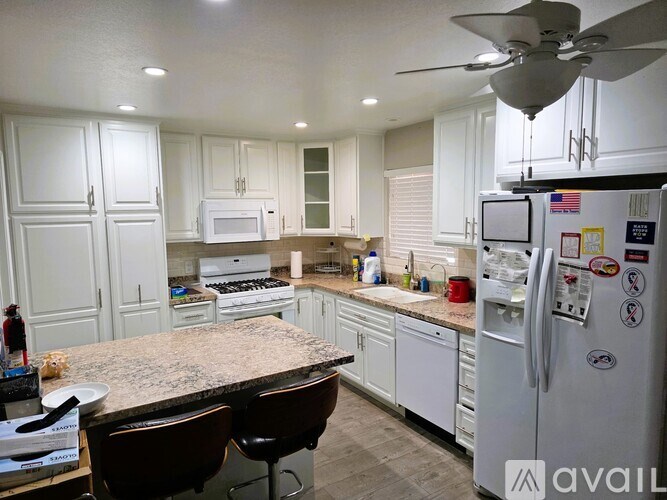 A kitchen with white cabinets and a granite countertop.