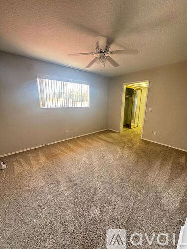 A room with a ceiling fan and a window with blinds.