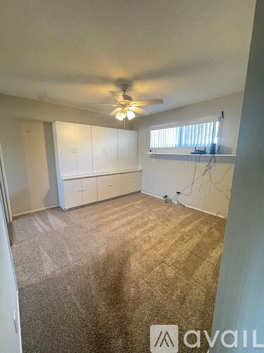A room with a ceiling fan and carpeted floor.