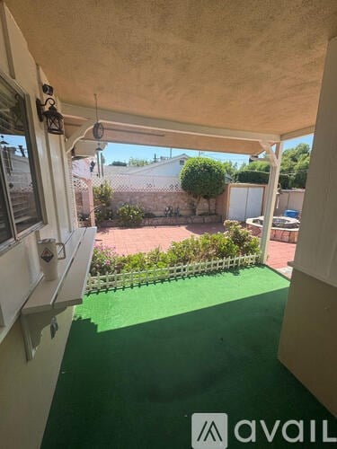A patio with a white pergola and red tiled floor.