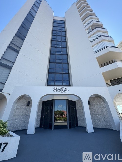 A white building with a glass entrance and a sign that says "Parking".