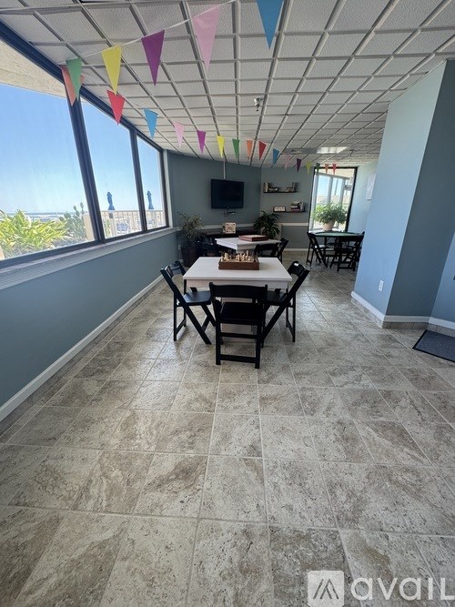 A room with a table and chairs and a window overlooking the beach.
