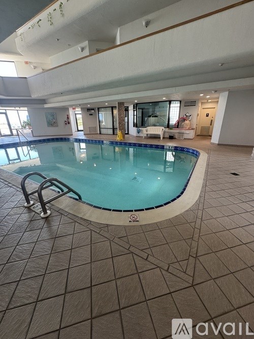 A large indoor swimming pool with a tiled floor and a diving board.