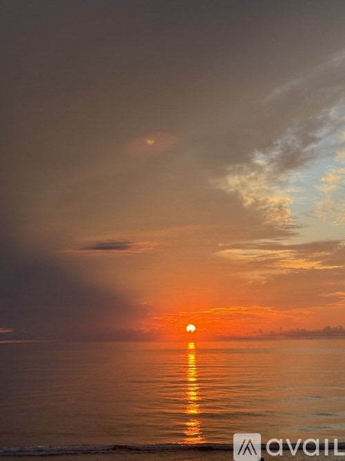 The sun is setting over the ocean, casting a warm glow on the water.