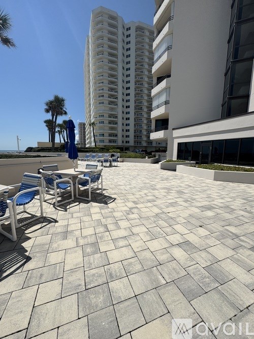 A patio with chairs and umbrellas is in front of a building.
