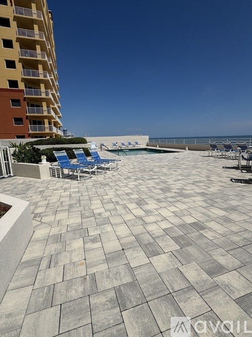 A patio with a tiled floor and chairs overlooking the beach.