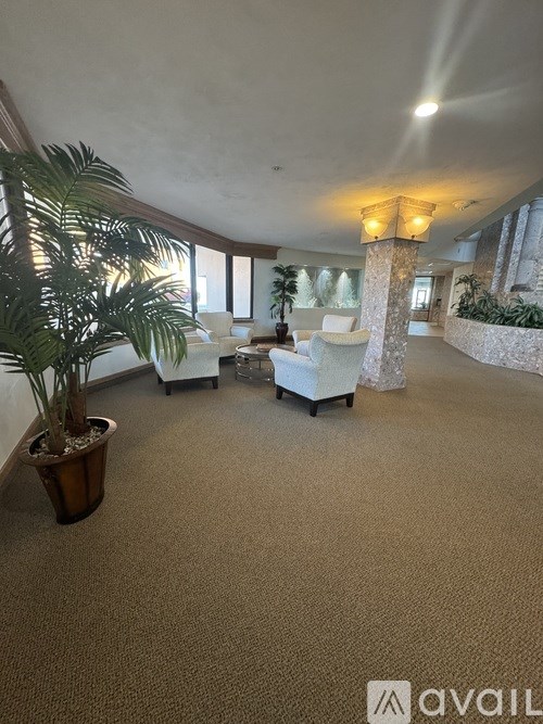 A living room with a couch, chair, and potted plant.
