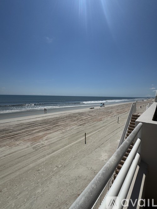 A sunny day at the beach with people walking and playing.