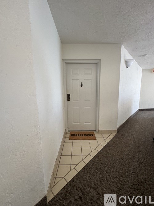 A hallway with a door and a mat that says "WE CLOSE".