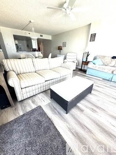 A living room with a white couch and a grey rug.