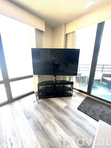 A black television is on a stand in a room with a grey rug.