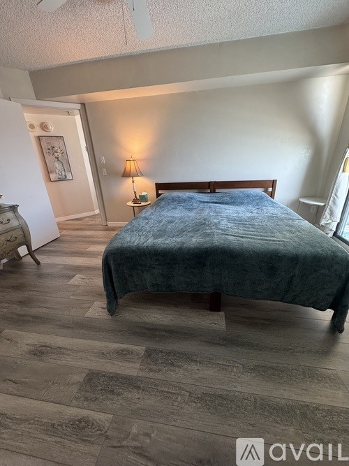 A bedroom with a bed, nightstand, lamp, and a dresser.