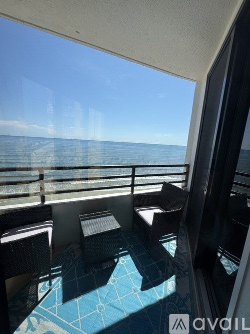 A balcony with chairs and a table overlooking the ocean.