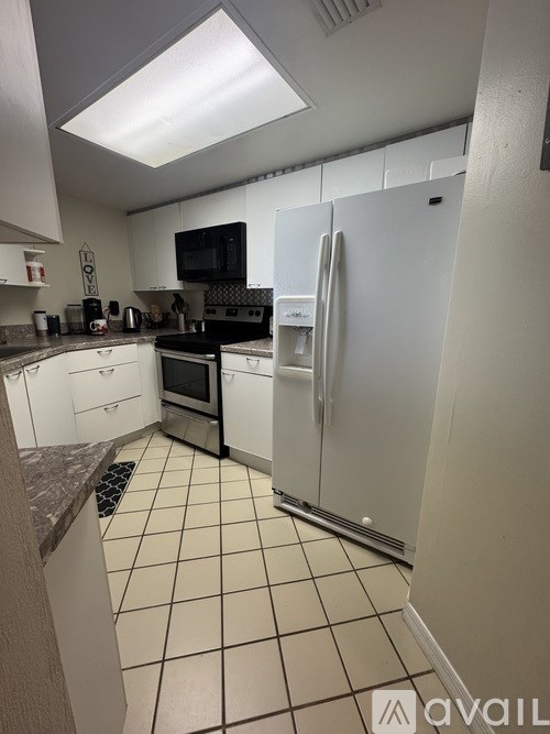 A kitchen with white cabinets and a white fridge.