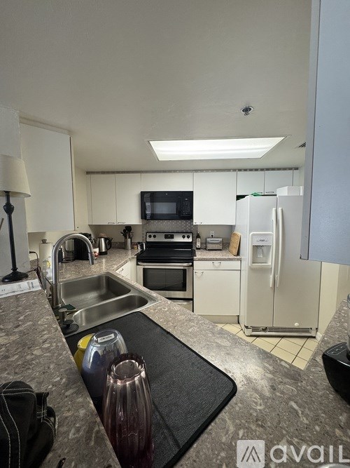 A kitchen with a sink, refrigerator, and microwave.