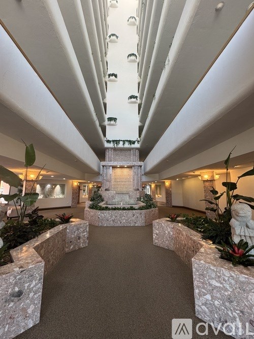A long hallway with a fountain in the middle and plants on the sides.