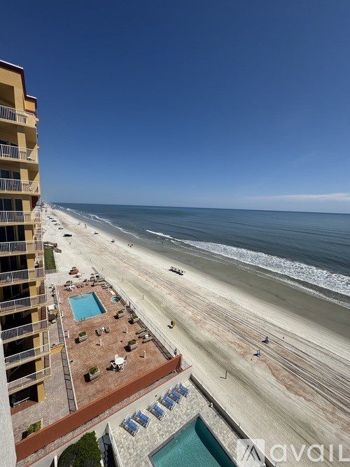 A beachfront apartment complex with a pool and beach in the background.