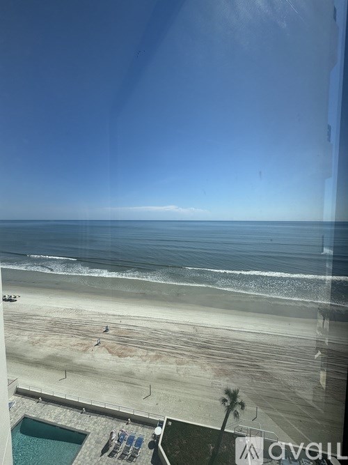 A view of a beach from a high vantage point with a pool and palm trees.