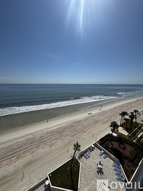 A beach with a clear blue sky and the sun shining brightly.