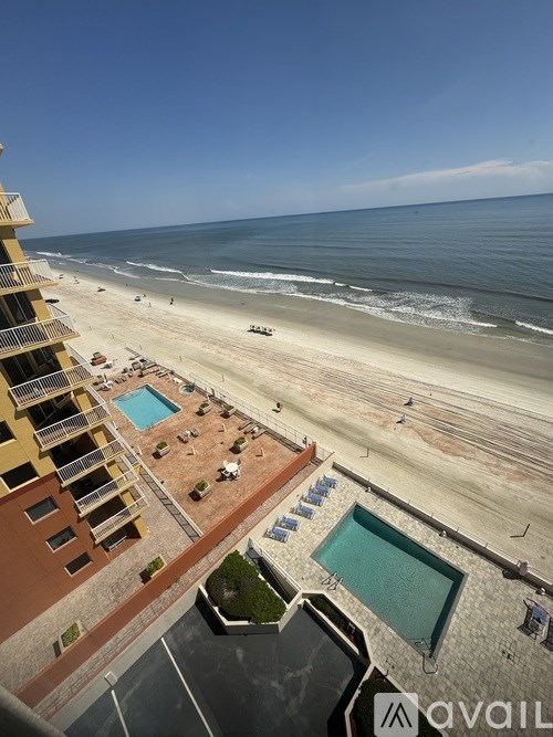 A beachfront hotel with a swimming pool and beach in the background.