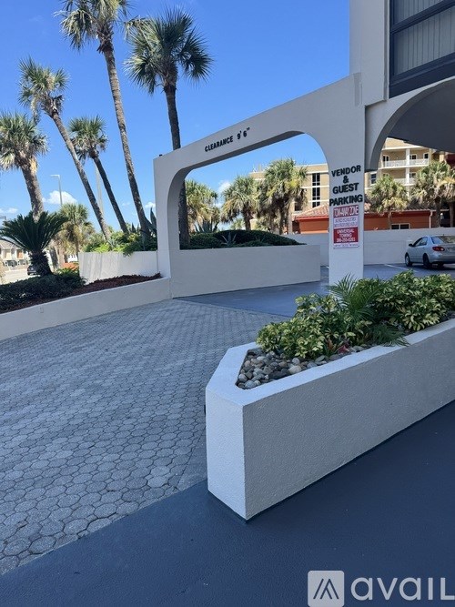 A white planter box with green plants in front of a building with a sign that says "VENDOR GUEST PARKING".