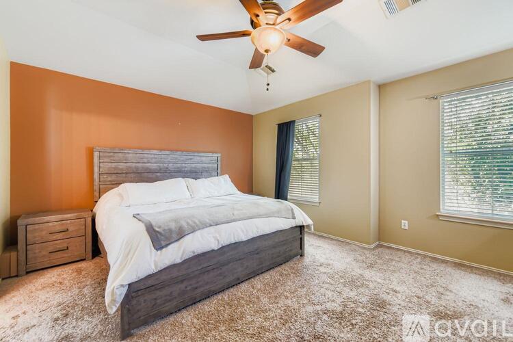 A bedroom with a bed, nightstands, and a ceiling fan.