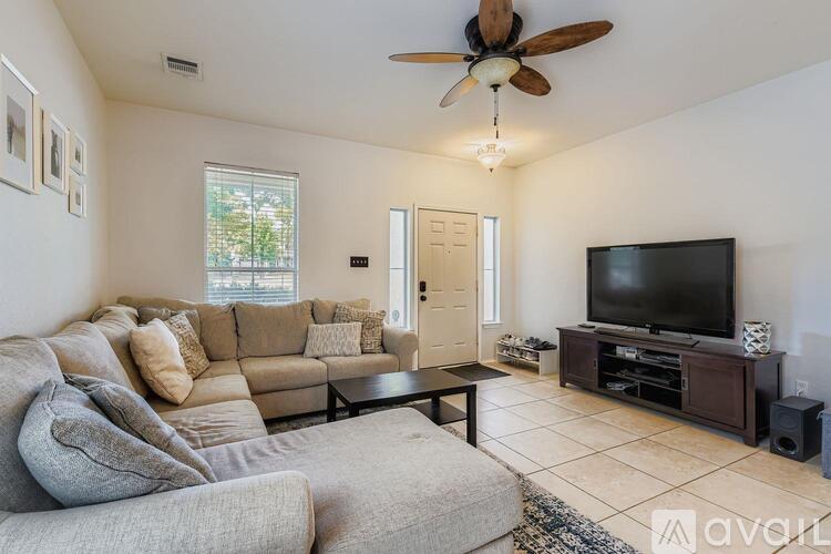 A living room with a grey couch, a brown sofa, a black television, and a ceiling fan.