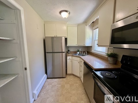 A kitchen with a stainless steel refrigerator and black stove top.