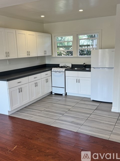 A kitchen with white cabinets and a white fridge.